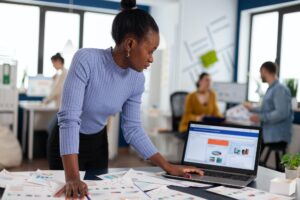 African woman scorlling on laptop looking at charts