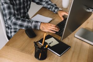 cropped shot of man in plaid shirt using computer at workplace