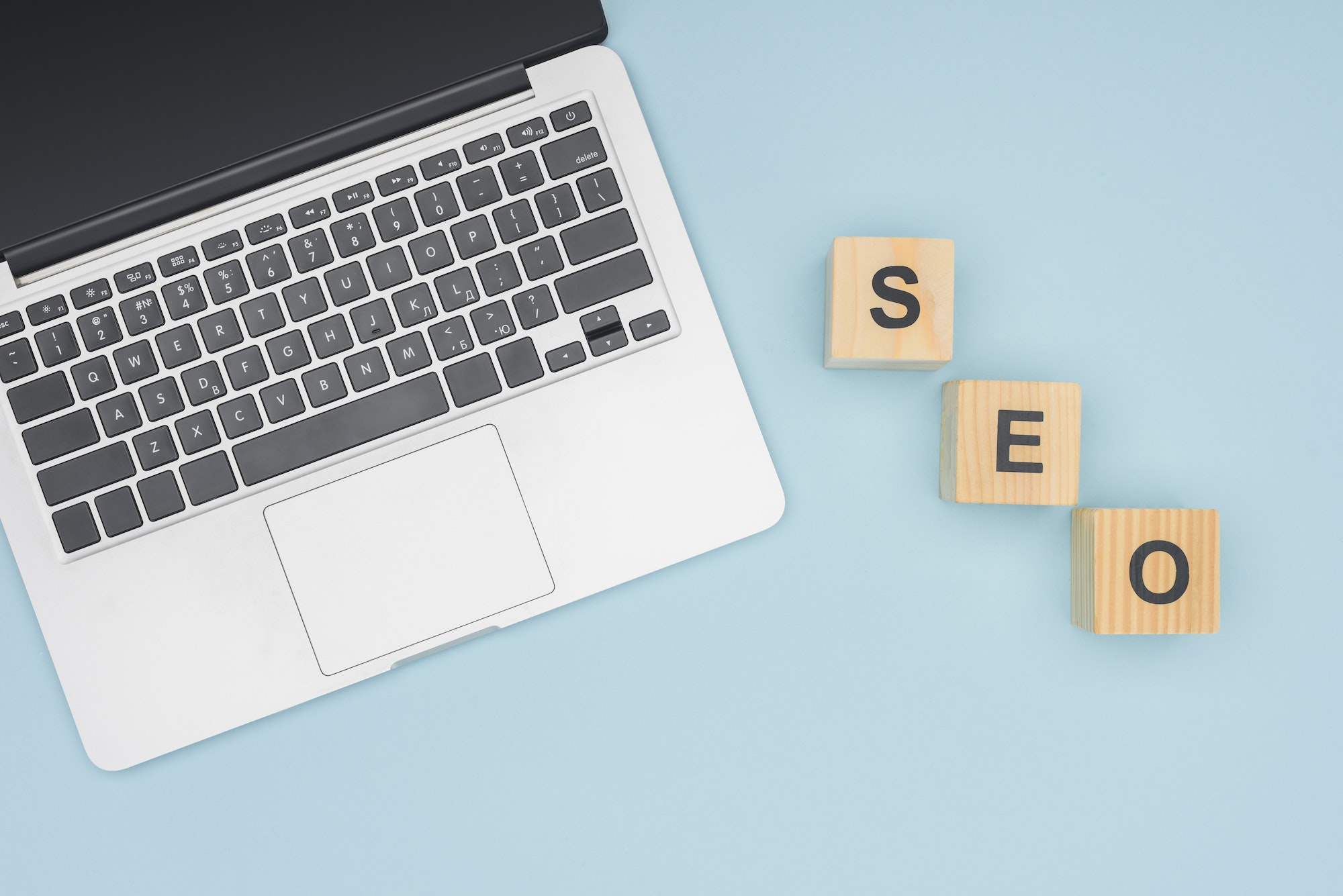 Top view of digital device near wooden cubes on light blue background