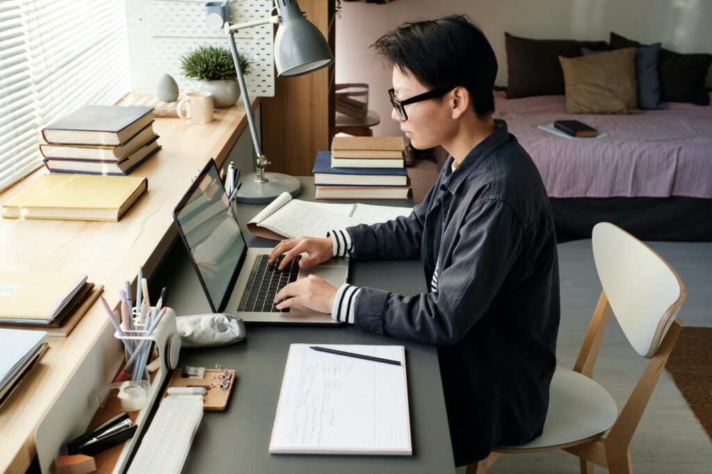 Asian student guy using laptop